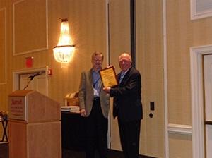 richard-arnott Richard Arnott (right) receiving a plaque from Vernon Henderson